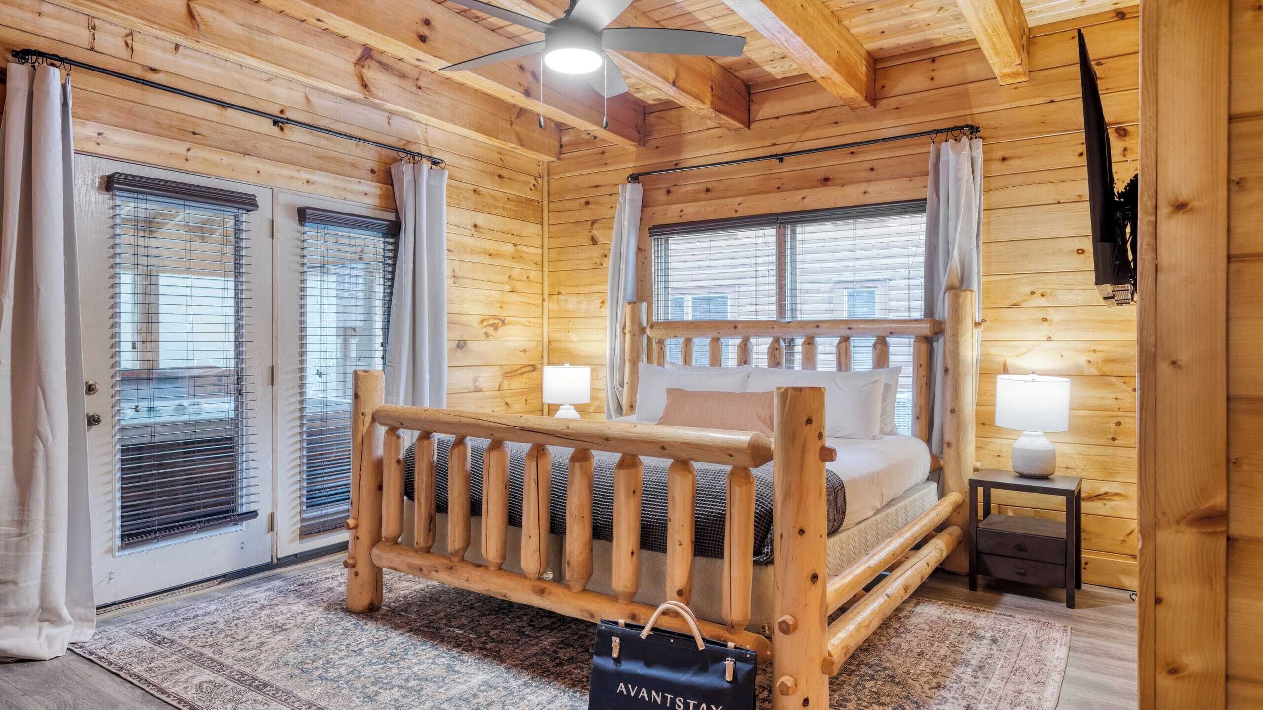 Ein Schlafzimmer in einer Blockhütte mit einem Holzbett, zwei Nachttischlampen und einem Deckenventilator.
