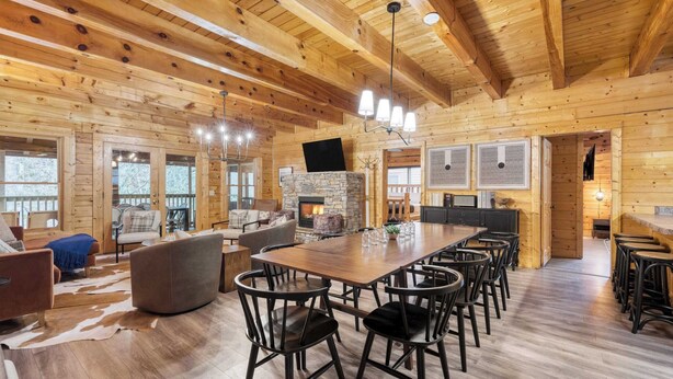 A spacious wooden cabin with a large dining table, multiple chairs, a fireplace, and a cozy seating area. - Brookshore by Avantstay Relaxing Backyard Creek, 10mins From Pigeon Forge (Pigeon Forge)