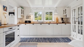 A modern kitchen with white cabinetry, a built-in oven, and a large window providing natural light. - Beautiful home in Vig with WiFi (Vig)