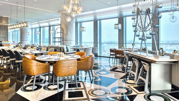 Un espace repas moderne avec des tables rondes, des sièges confortables et une grande structure décorative en forme de roue.