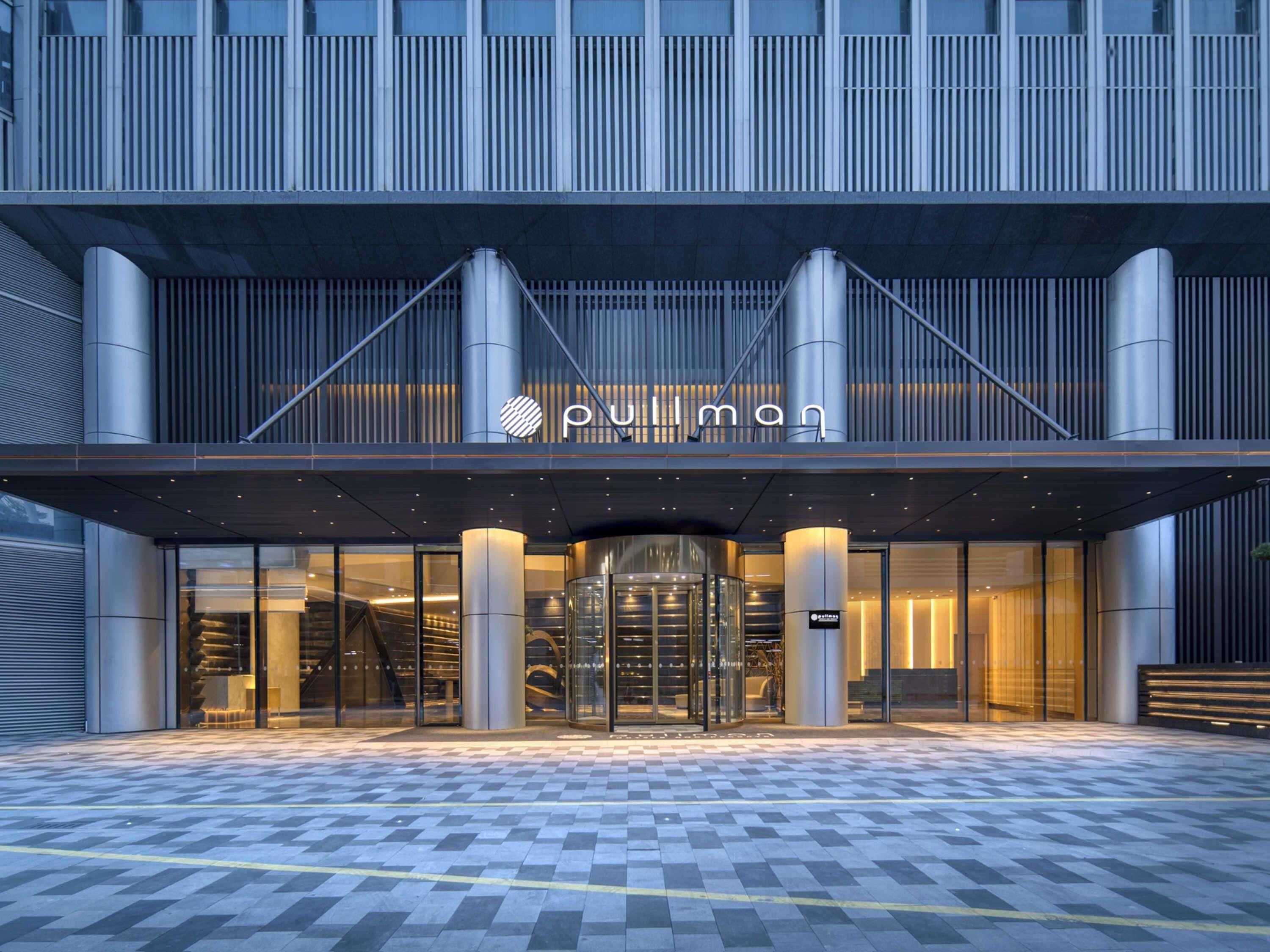 A modern building with a prominent entrance featuring a glass facade and a sign reading "Pullman".