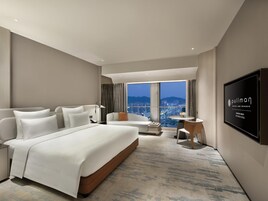 Una habitación de hotel moderna con una cama grande, un área de descanso y vistas a la ciudad.