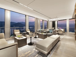 A modern hotel room with a panoramic city view, large windows, and contemporary furnishings.