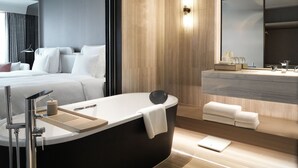 A modern hotel room with a large bed, a bathtub, a vanity with a mirror, and a wooden wall. - Pullman Shenzhen North (Shenzhen)