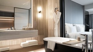 A modern bathroom with a bathtub, a vanity with a mirror, and a white robe hanging on the wall. - Pullman Shenzhen North (Shenzhen)