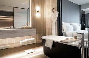 A modern bathroom with a bathtub, a vanity with a mirror, and a white robe hanging on the wall. - Pullman Shenzhen North (Shenzhen)