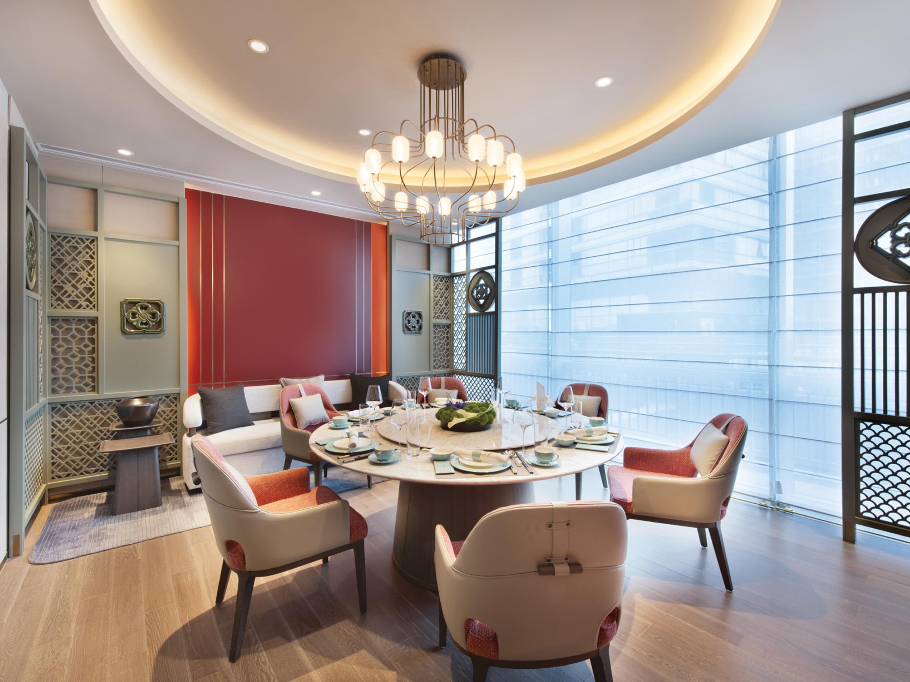 A modern dining area with a round table, chairs, and a chandelier.