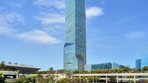 A modern skyscraper with a glass facade, surrounded by other buildings and a clear sky. - Pullman Shenzhen North (Shenzhen)