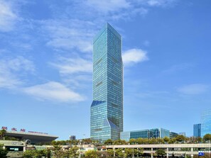 A modern skyscraper with a glass facade, surrounded by other buildings and a clear sky. - Pullman Shenzhen North (Shenzhen)