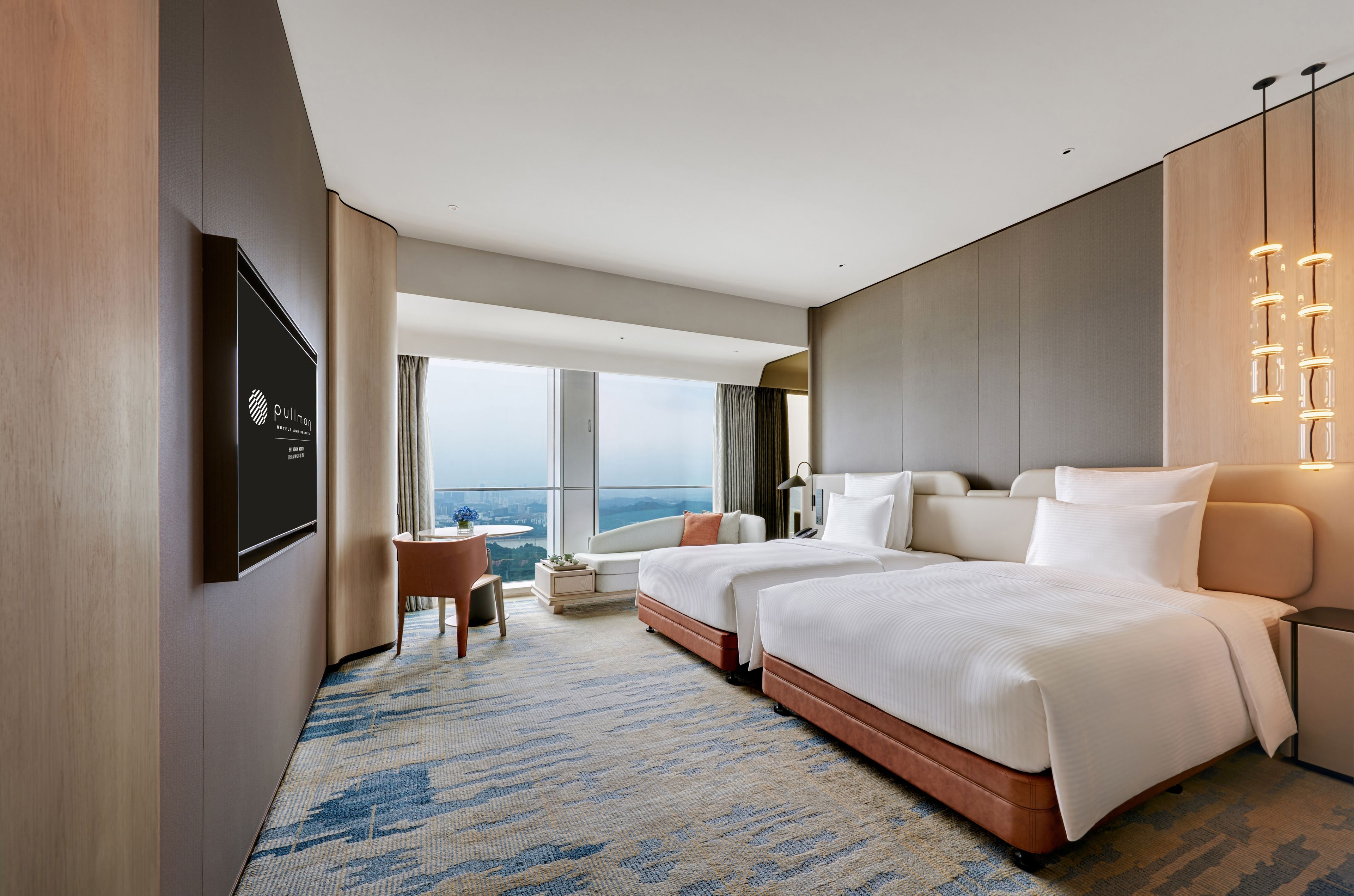 A hotel room with a large bed, a desk, and a view of the city.