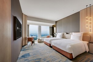 A hotel room with a large bed, a desk, and a view of the city.