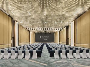 A conference room with rows of tables and chairs, a large screen at the front, and a ceiling with numerous lights. - Pullman Shenzhen North (Shenzhen)