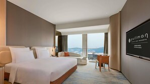 A hotel room with a large bed, a desk, a chair, a TV, and a view of the city. - Pullman Shenzhen North (Shenzhen)