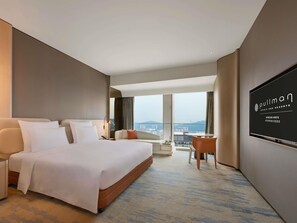 A hotel room with a large bed, a desk, a chair, a TV, and a view of the city. - Pullman Shenzhen North (Shenzhen)