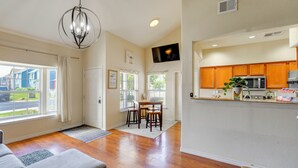 A spacious living room with hardwood flooring, a grey sofa, a dining area with a table and chairs, and a kitchen with wooden cabinets and a microwave. - Afton Townhome w/ Pool Access < Half-Mi to Boating (Afton)