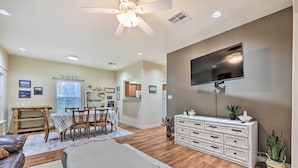 A spacious living room with a dining area, a TV mounted on the wall, and wooden flooring. - Walk to Lake: Townhome w/ Hot Tub in Afton! (Afton)
