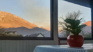 Een kamer met een groot raam dat uitkijkt op een bergachtig landschap.