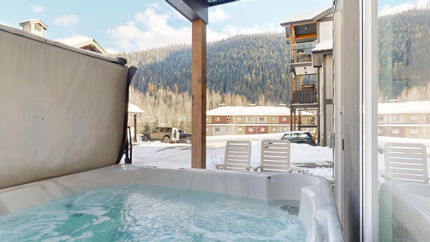 Un jacuzzi con vista a la montaña, mobiliario exterior y una zona cubierta.