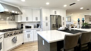A modern kitchen with white cabinets, stainless steel appliances, and a central island with bar stools.
