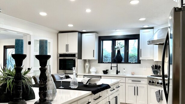 A modern kitchen with white cabinetry, a central island, and a stainless steel refrigerator.
