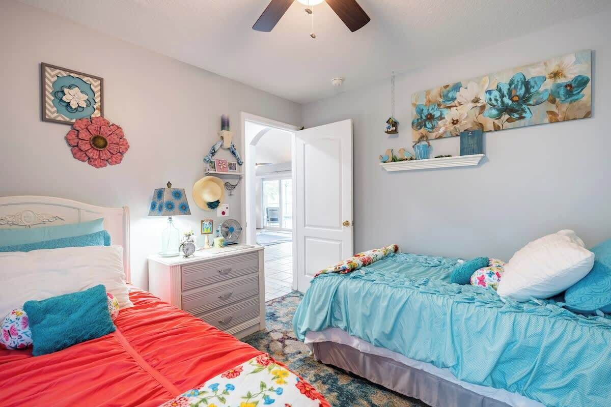 Une chambre avec deux lits, une commode, une table de chevet et un ventilateur de plafond.