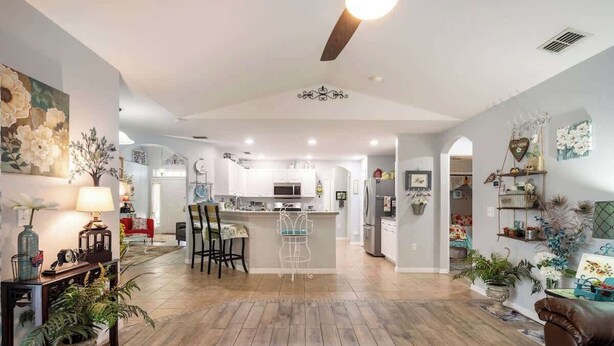 A spacious living area with a kitchen in the background, a dining area with chairs, and a coffee table. - 25%off/Close to Disney/Hot Tub/Private Pool/Fenced (Davenport)