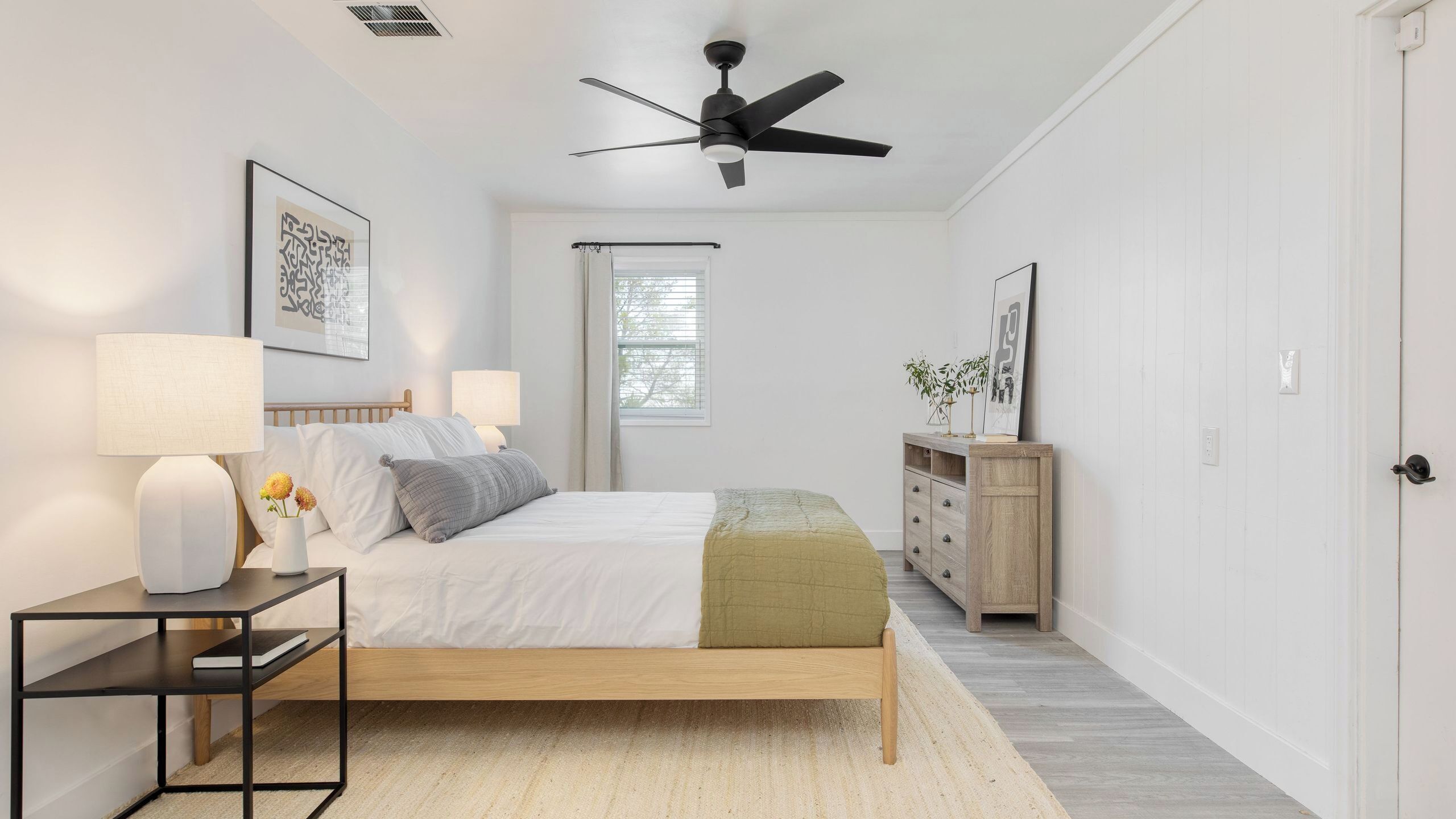 A bedroom with a bed, bedside tables, a ceiling fan, a window, and a dresser.