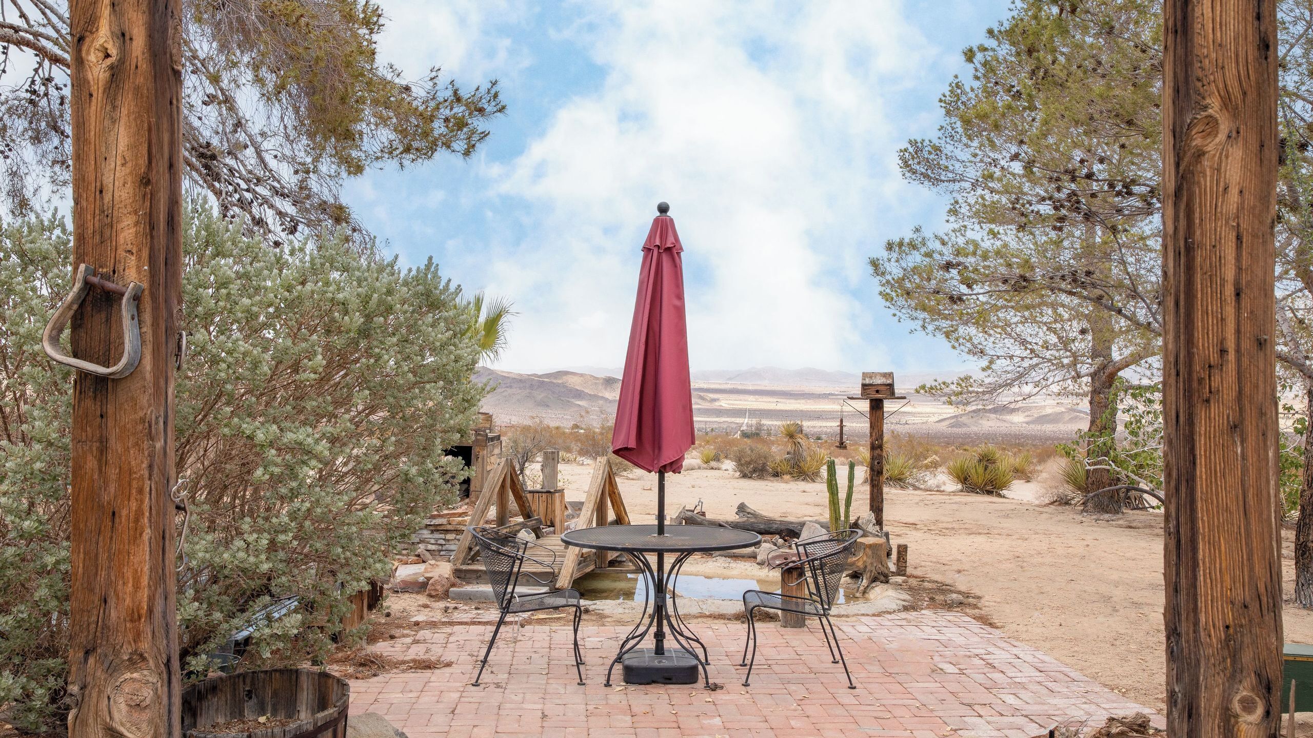 Une terrasse extérieure avec une table et des chaises, un parasol rouge et une vue sur le paysage désertique.