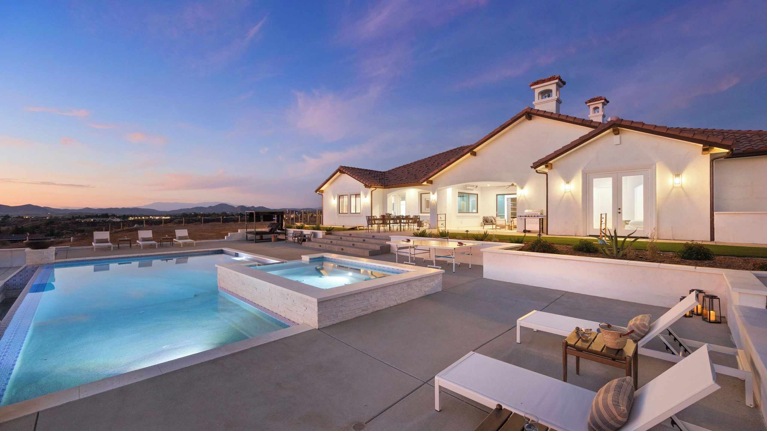 Une maison moderne dotée d’une piscine, d’un espace salon extérieur et offrant une vue sur les montagnes.