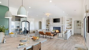 Ein modernes Wohnzimmer mit Kamin, Sitzgruppe und Essbereich mit gedecktem Tisch.
