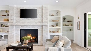 Ein Wohnzimmer mit Kamin, Flachbildfernseher und Bücherregal.