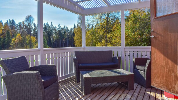 A covered outdoor seating area with wicker furniture and a wooden deck. - Cozy home in Kyrkhult with WiFi (Kyrkhult)