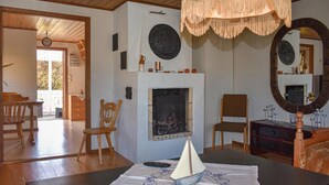 A cozy living room with a fireplace, wooden furniture, and a decorative sailboat centerpiece. - Cozy home in Kyrkhult with WiFi (Kyrkhult)