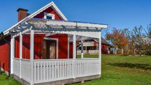 A red wooden house with a white porch and a small balcony. - Cozy home in Kyrkhult with WiFi (Kyrkhult)