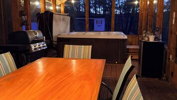 Une terrasse en bois avec une table et des chaises, un barbecue et un jacuzzi.