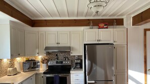 Una cocina con gabinetes blancos, un refrigerador de acero inoxidable, una estufa y un microondas.
