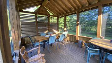 Relax in a charming outdoor space with a wooden deck, tables, and comfortable seating.