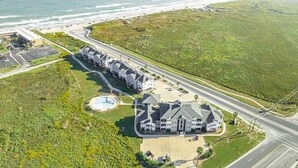 An aerial view of a coastal residential area with a large house, a swimming pool, and a parking lot. - 2-Minute Walk to the Beach + Pool Views! (Corpus Christi)