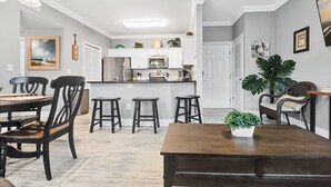 A modern kitchen with white cabinets, a central island, and bar stools. - 2-Minute Walk to the Beach + Pool Views! (Corpus Christi)