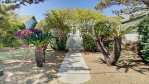 A pathway leading to a house surrounded by various plants and trees. - Red Maple by Avantstay Walk to Folly Beach (Folly Beach)