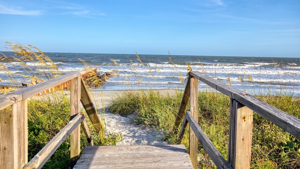 A wooden boardwalk leading to the beach with waves crashing in the background. - Red Maple by Avantstay Walk to Folly Beach (Folly Beach)