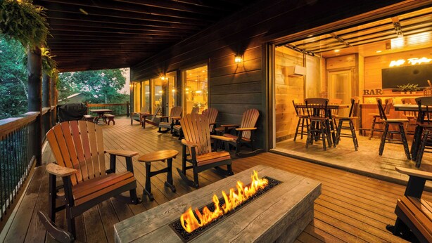 Eine Terrasse im Freien mit Holzmöbeln, einer Feuerstelle und einer Bar.