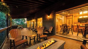 An outdoor deck with wooden furniture, a fire pit, and a bar area. - Wanderer by Avantstay Sleeps 34, A+ Custom Smokies Cabin (Sevierville)