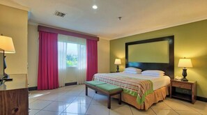 Relax in comfort with a large bed, bedside tables, and a bench, surrounded by a clean and modern space.