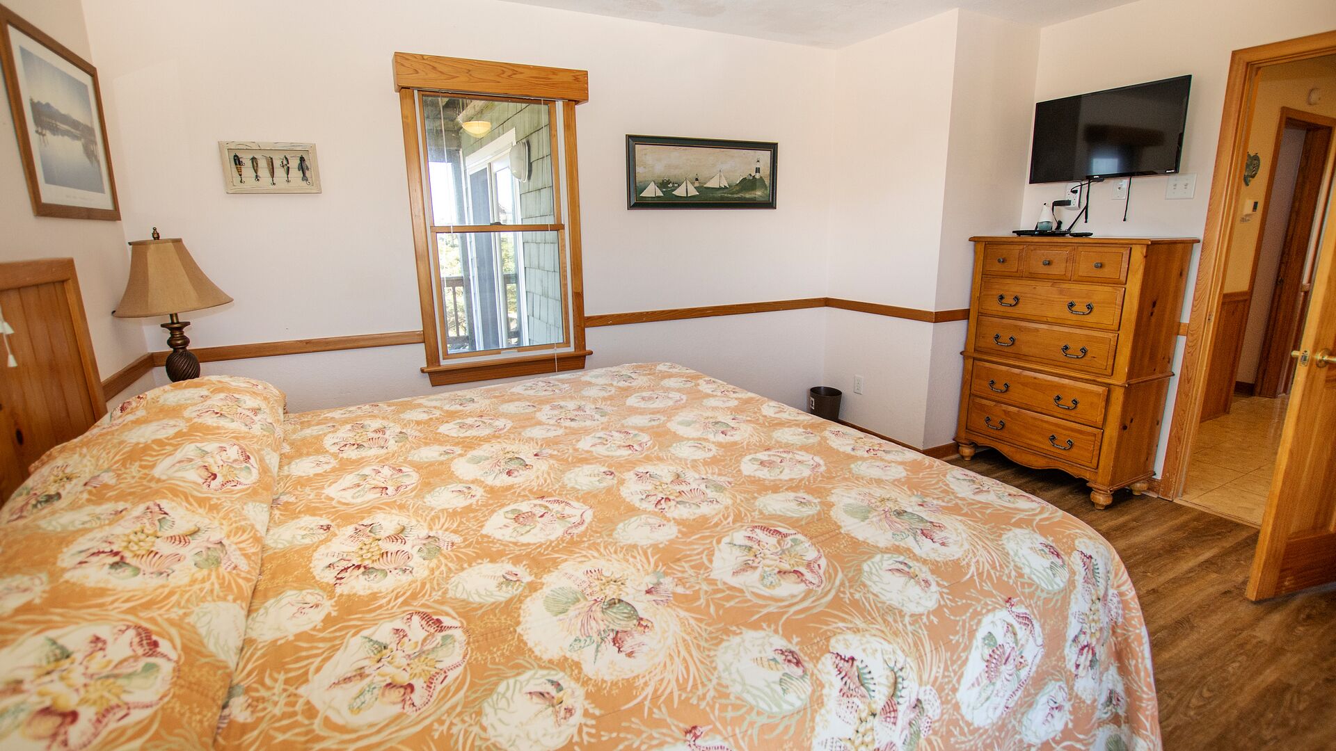 A bedroom with a bed, a dresser, a television, and a window.
