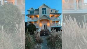 A two-story house with a central entrance, multiple balconies, and a well-lit front porch. - Semi-Oceanfront, Private Pool, Hot Tub, Ocean Views (Avon)