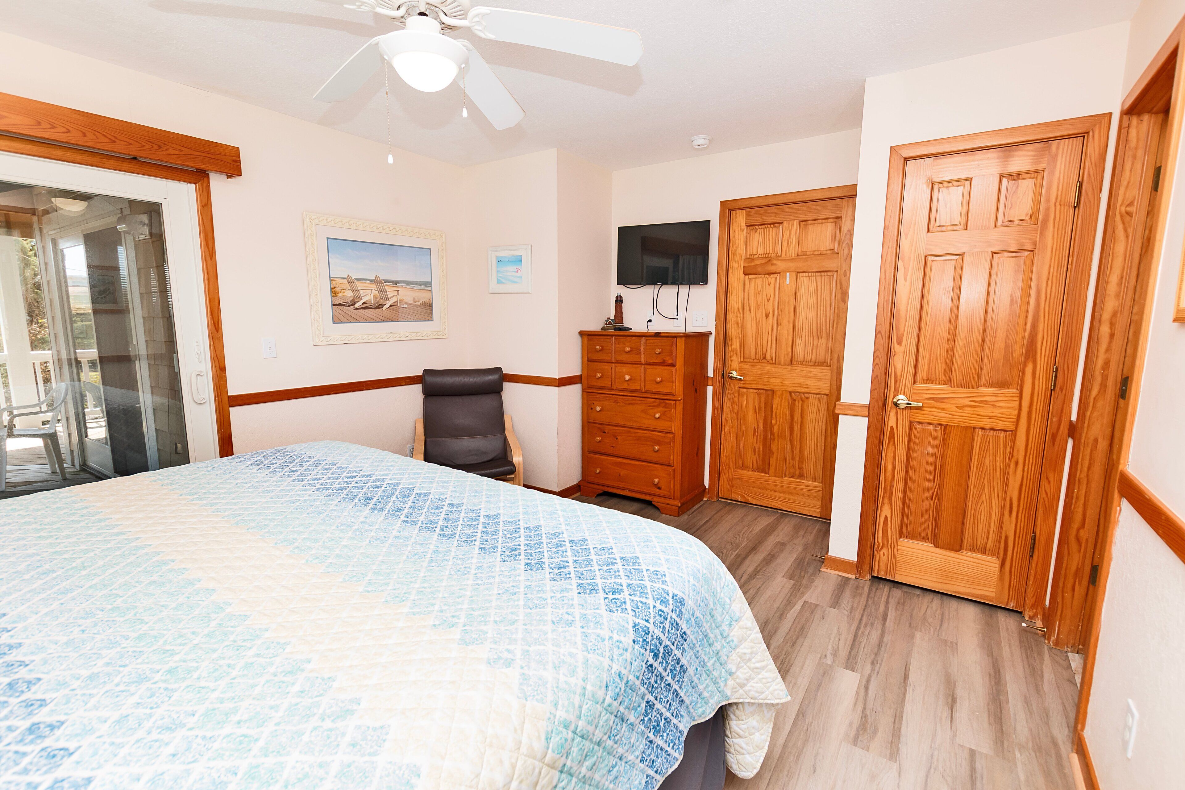A bedroom with a bed, a chair, a dresser, and a television.