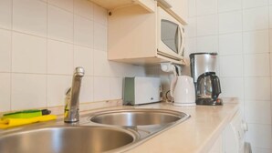 A kitchen with a stainless steel sink, a microwave, a toaster, and a coffee maker. - Cozy Two Bedroom Apt in Central Alfama | With A/c by Lisbeyond (Lisboa)