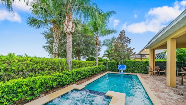 Une piscine avec un jacuzzi, entourée d’une végétation luxuriante et de palmiers.