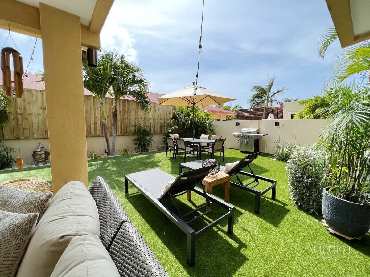 Un patio con un sofá, dos sillones, una mesa y una parrilla.